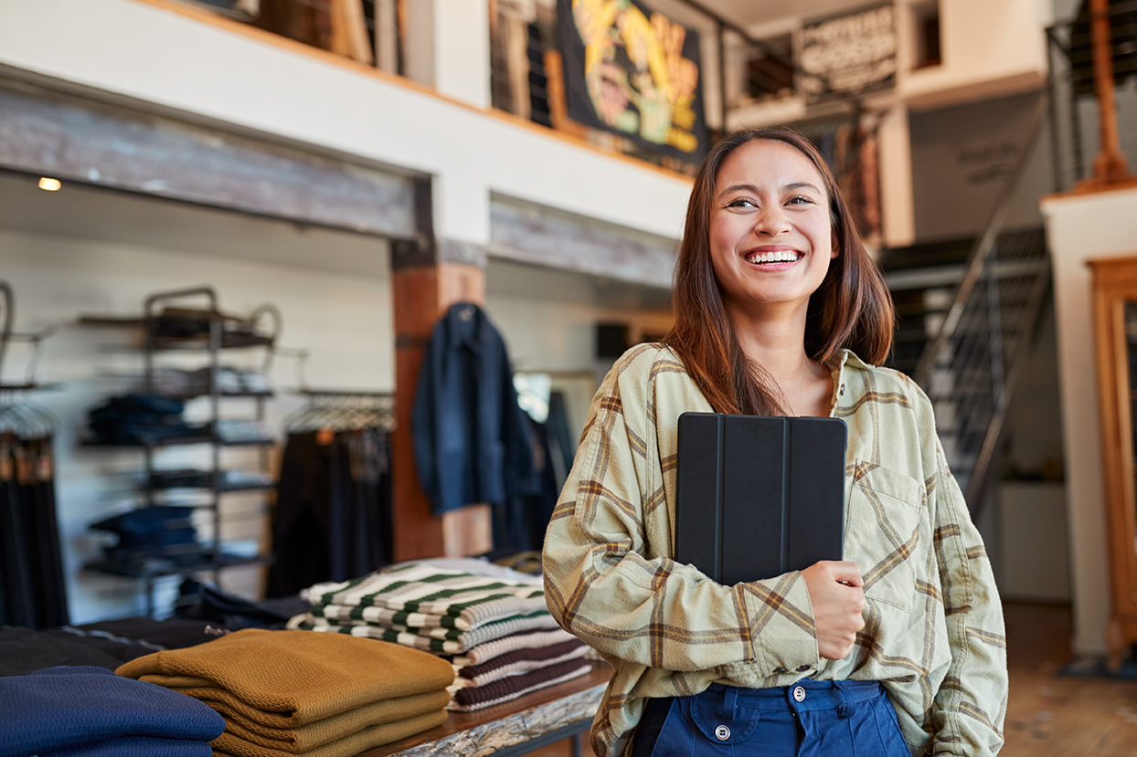Clothing store owner smiling with tablet